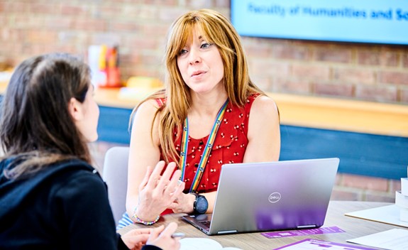 A Librarian talking to a student with a laptop during a drop-in.